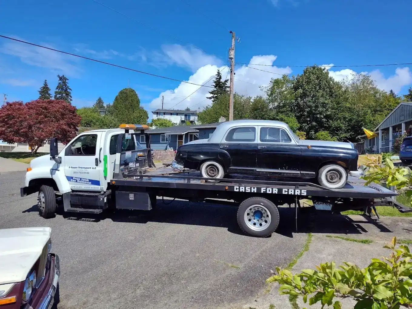 T-Town flatbed tow truck hauling an old car